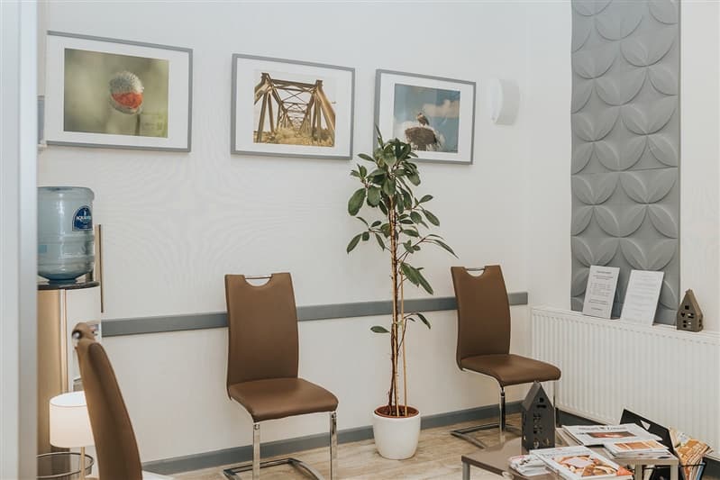 Wartezimmer mit Sitzgelegenheiten, Wasserspender und Bildern an der Wand